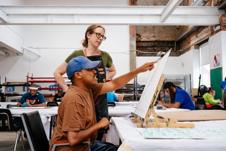 Two people working together on a project in an art studio setting.